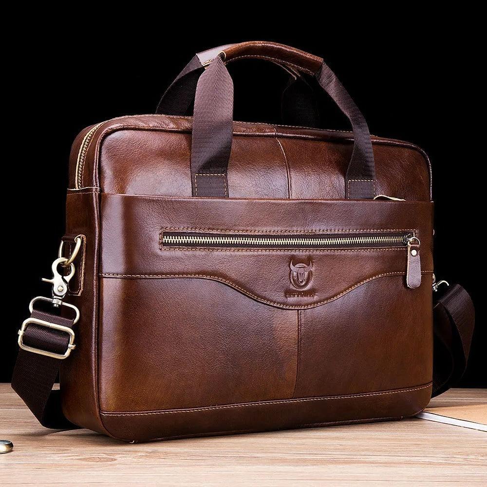 Bolsa masculina grande de cuero marrón con asas y correa ajustable sobre mesa de madera.